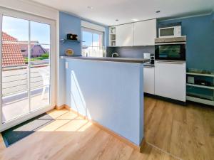 a kitchen with white cabinets and a large window at Klipper in Greetsiel