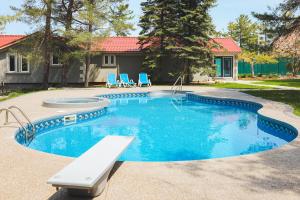 a swimming pool with blue chairs and a house at The Lighthouse Cottage Four in Wasaga Beach +11 photos
