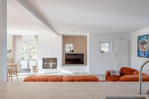 a living room with orange couches and a tv at Maison Ensor - Lux Living in De Panne