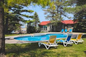 a swimming pool with chairs and a house at The Lighthouse Cottage Four in Wasaga Beach