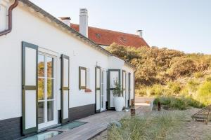 Cette maison blanche dispose de grandes fenêtres. dans l'établissement Maison Ensor - Lux Living, à La Panne