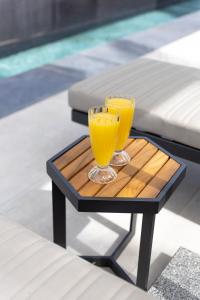 two glasses of orange juice on a table next to a pool at Alaia Resort- Had Nes אלאיה ריזורט - חד נס in Had Nes