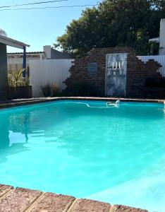 a swimming pool with blue water in a yard at Tuinhuis in Oudtshoorn