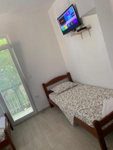 a small bedroom with a bed and a tv on the wall at LamijaApartmani in Sutomore