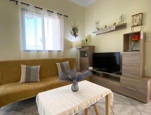a living room with a couch and a tv at Sunny Apartment Amaliada in Amaliás