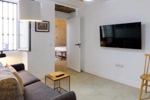a living room with a couch and a tv on a wall at Casa de los Venerables in Seville