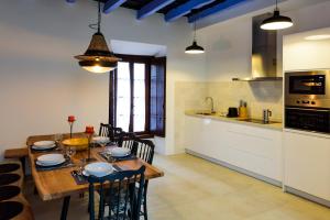 cocina y comedor con mesa de madera y sillas en Casa de los Venerables en Sevilla