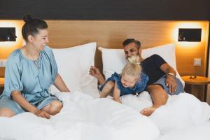un hombre y una mujer sentados en una cama con una niña en TILL Naturhotel - Self-Check-In en Satteins