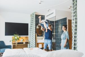 two people standing in a bedroom with a person jumping on a bed at TILL Naturhotel - Self-Check-In in Satteins