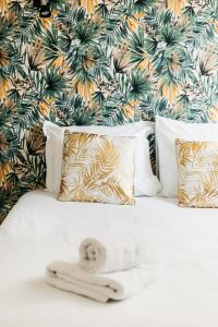 cama blanca con almohadas y pared de flores en Hôtel Restaurant La Voile - Le Dock'er, en Locmariaquer