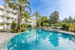 ポルト・ダ・ポリェンサにあるHotel Illa d'Or & Club Apts 4* Supのヤシの木とコンドミニアムがある大型スイミングプール