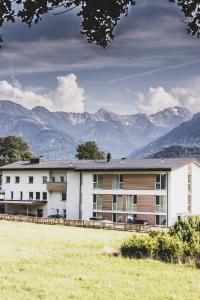 a large white building with mountains in the background at TILL Naturhotel - Self-Check-In in Satteins