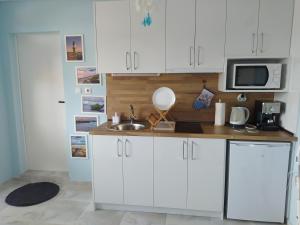 a kitchen with white cabinets and a sink and a microwave at Апартамент White apartment град Китен in Kiten +14 photos