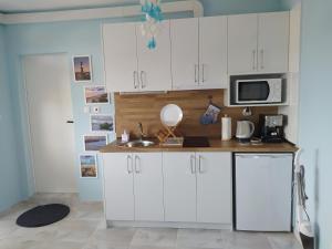uma cozinha com armários brancos e um lavatório em Апартамент White apartment град Китен em Kiten