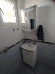 uma casa de banho branca com um lavatório e uma janela em Апартамент White apartment град Китен em Kiten