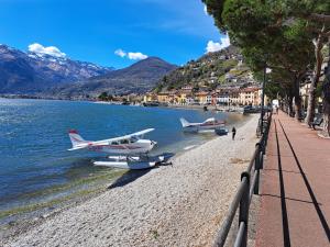 two planes parked on a beach next to the water at Immobillario - Maison Felix in Gravedona