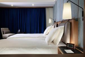 a bedroom with a large white bed with blue curtains at Hotel Collective in Naha