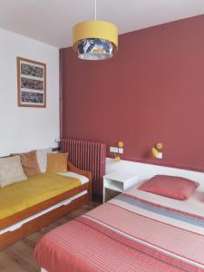 - une chambre avec 2 lits et un mur rouge dans l'établissement Les Camélias, à Le Mont-Dore