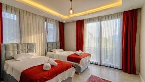 a bedroom with two beds with red curtains and windows at Göcek Villa Can in Belenpınar +31 photos