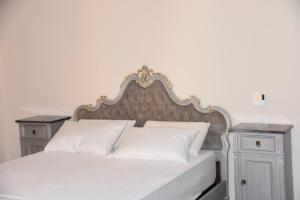 een bed met witte kussens en 2 nachtkastjes bij Le Dame Manfrede in Faenza