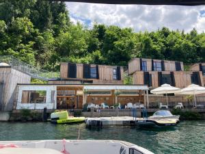 una casa en el agua con barcos delante en Kantor See-Chalets am Millstätter See, en Rothenthurn