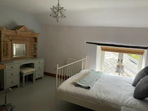 a bedroom with a bed and a dresser and a mirror at Berehayes Farmhouse in Bridport +36 photos