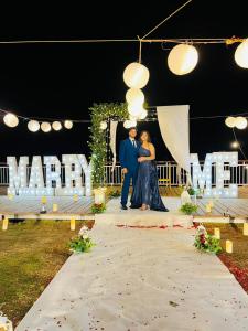 a bride and groom standing in front of a mnm sign at Maargit Beach Resort in Mandrem