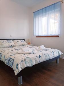 Bett in einem Zimmer mit Fenster und Tagesdecke in der Unterkunft Vacation House Rosa in Supetarska Draga