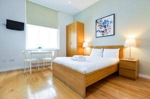 1 dormitorio con cama, mesa y escritorio en Notting Hill Serviced Apartments by Concept Apartments, en Londres