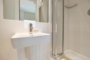 y baño blanco con lavabo y ducha. en Notting Hill Serviced Apartments by Concept Apartments, en Londres