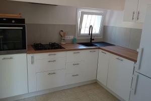 a kitchen with white cabinets and a counter top at Grand appartement, 2 chambres et jardin in Nîmes