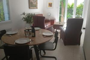 una mesa de comedor y sillas con una botella de vino en Grand appartement, 2 chambres et jardin, en Nimes