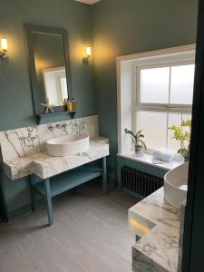 Baño con 2 lavabos, espejo y ventana en Hamilton Lodge: a 6 bedroom seaside Holiday Home hosting Happiness, en Kent