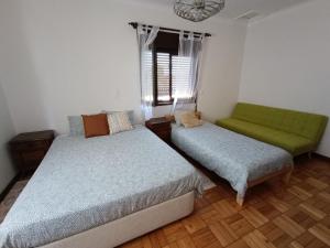 1 dormitorio con 2 camas y 1 sofá verde en Casa da Rosa en Arcozelo