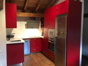 cocina con armarios rojos y nevera de acero inoxidable en Apartamento Cabariezo, en Cabezón de Liébana
