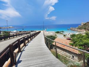 eine hölzerne Promenade, die zu einem Strand und dem Meer führt in der Unterkunft Villa Cala d'Oro santa teresa di gallura in Santa Teresa Gallura