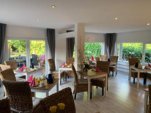 a dining room with tables and chairs and windows at Gästehaus Schwentineblick in Malente +54 photos