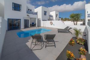 a patio with chairs and a pool in front of a house at Villas Yaiza in Playa Blanca +34 photos