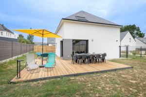 eine Terrasse mit Tischen und Stühlen und einem gelben Regenschirm in der Unterkunft Instants detente en famille au Tour-du Parc in Le Tour-du-Parc