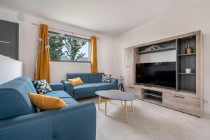 sala de estar con sofá azul y TV en Instants detente en famille au Tour-du Parc, en Le Tour-du-Parc