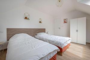 Habitación con 2 camas, paredes blancas y suelo de madera. en Instants detente en famille au Tour-du Parc, en Le Tour-du-Parc