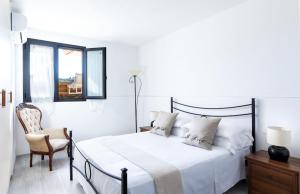 een witte slaapkamer met een bed en een stoel bij Casa Papa in Castelfiorentino