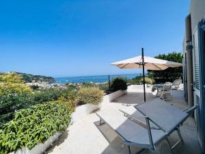 une terrasse avec une table et un parasol et l'océan dans l'établissement ELISABETH GARDEN APARTMENT, à Ischia
