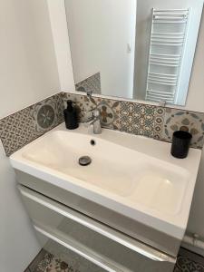 lavabo blanco en el baño con espejo en Gîte les Tilleuls en Gouchaupré