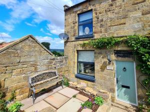 a stone building with a blue door and a bench at Ingleside Cottage in Glaisdale