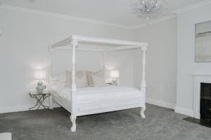 een slaapkamer met een wit hemelbed en een open haard bij Highfield Hall in Mold