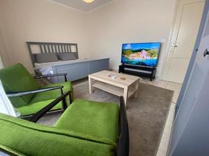 a living room with green chairs and a television at Madinaty Hotel in Madinaty