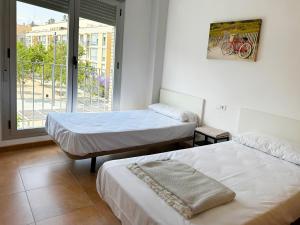 a room with two beds and a window with a bike on the wall at Apartamentos Benicarló 3000 in Benicarló