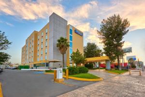 un grand bâtiment avec des palmiers devant lui dans l'établissement City Express by Marriott Saltillo Norte, à Saltillo