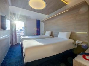 een hotelkamer met 2 bedden en een raam bij ibis Styles La Rochelle Centre in La Rochelle